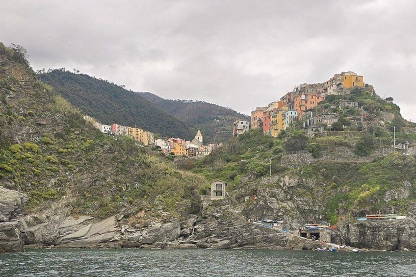 A coastal village with colorful buildings on a hillside, a small tower-like structure, and rocky terrain. 2