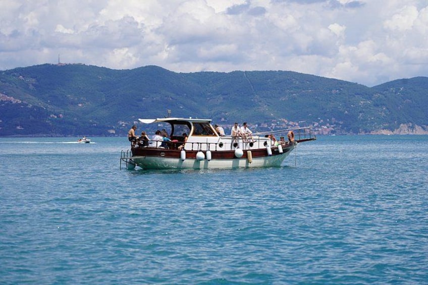 A boat with passengers on a calm sea, a distant shoreline, and a clear sky. 5