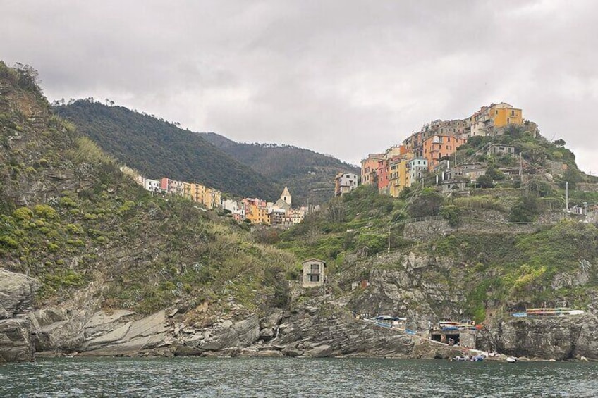 Un village côtier avec des bâtiments aux couleurs vives, situé sur une colline, doté d’un littoral rocheux et d’une petite tour. 2