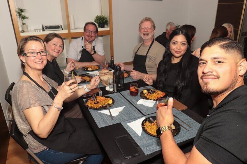 A group of people sitting around a table with plates of food and drinks. 1