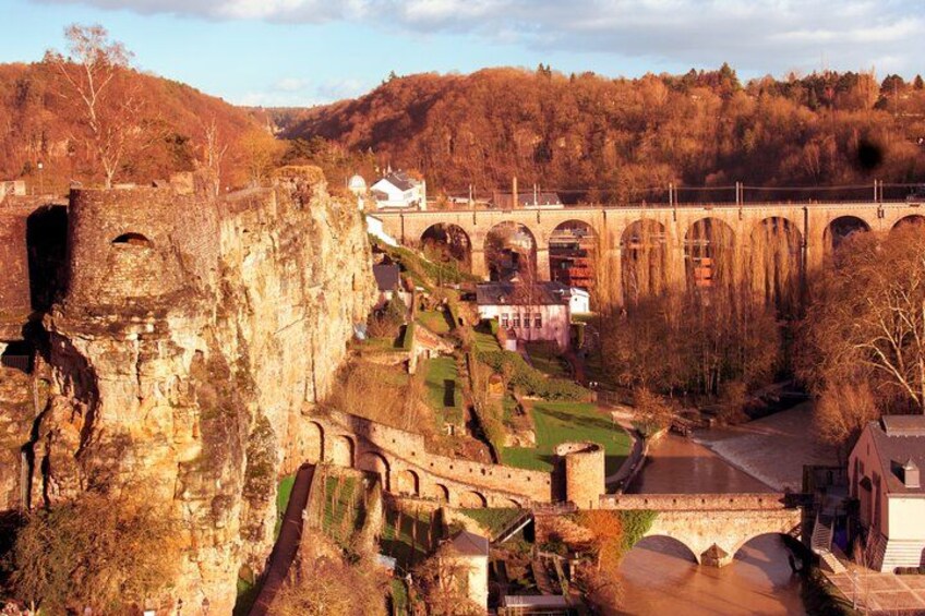 A historic stone bridge, a castle ruin, and a modern building in a valley. 3