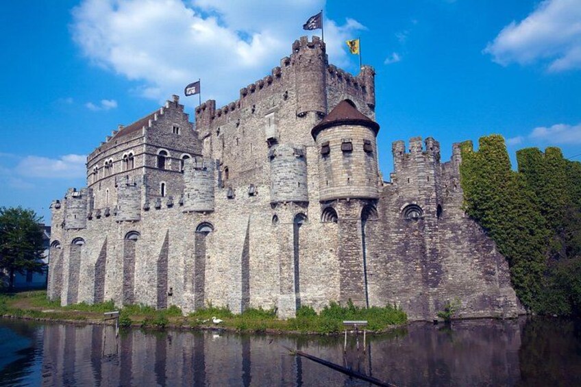 Un castillo histórico con un foso, rodeado de vegetación y un cielo despejado. 3