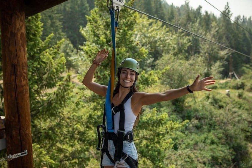 A person zip-lining with a harness and helmet, surrounded by a forested landscape. 2