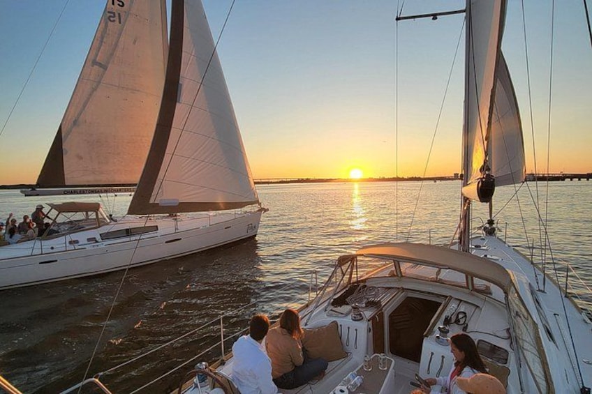 Una barca a vela con due vele, un tramonto sullo sfondo e acqua calma. 1