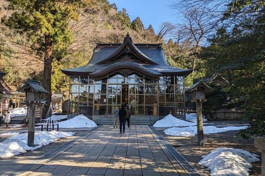 A traditional Japanese building with a tiled walkway leading to it, surrounded by snow and trees. 3