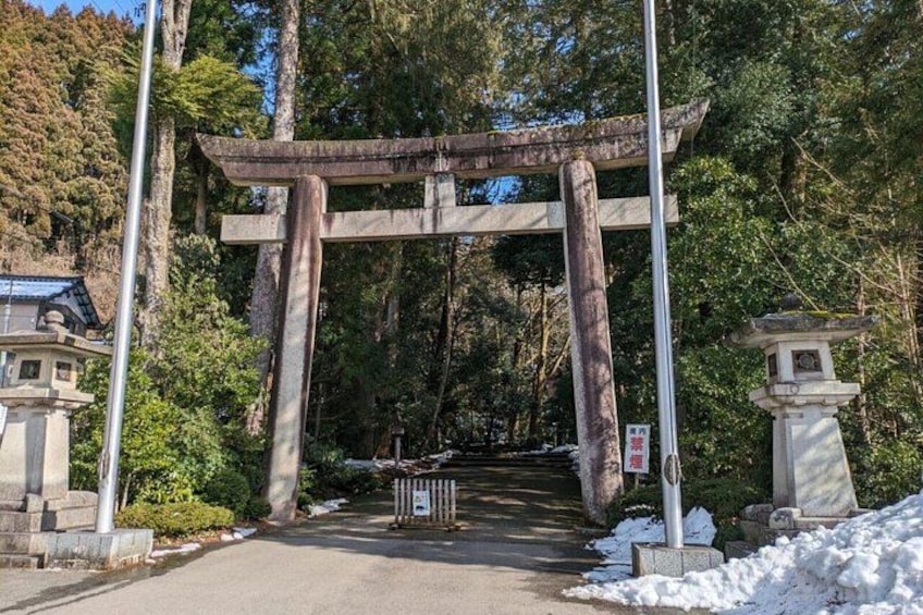 A traditional Japanese torii gate with a stone lantern and a shrine in the background. 5