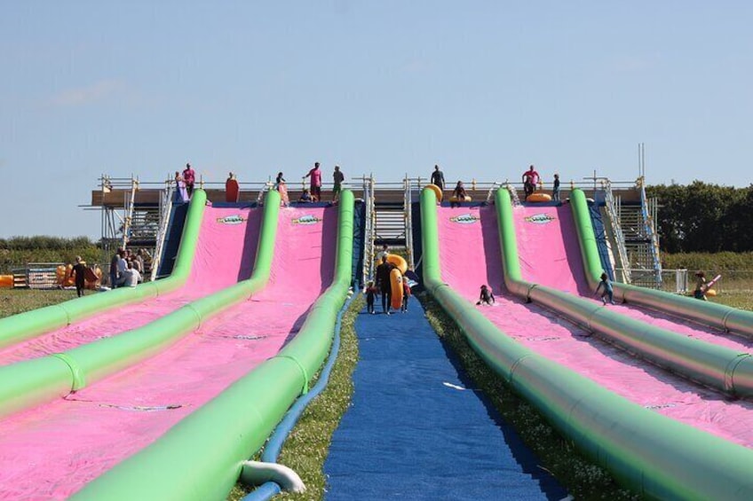 Un toboggan aquatique à plusieurs pistes, avec des parois vertes et roses, et une partie inférieure bleue. 4
