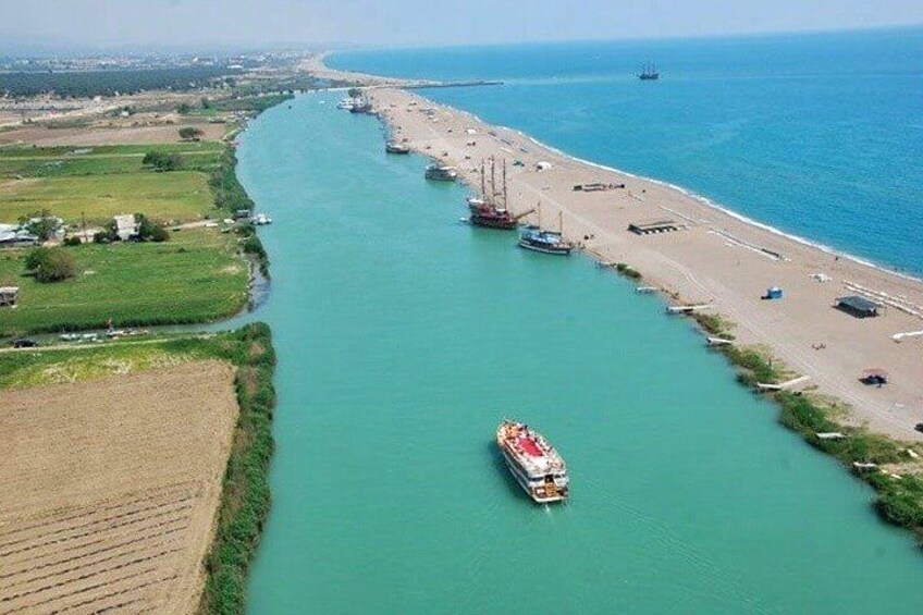 A river with a boat, a beach, and a distant cityscape. 3