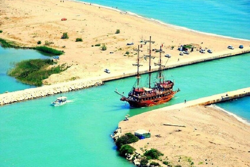 A coastal area with a large ship docked at a pier, a sandy beach, and a small boat in the water. 2