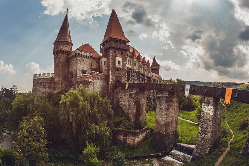 Un castillo histórico con múltiples torres, un puente y abundante vegetación. 1