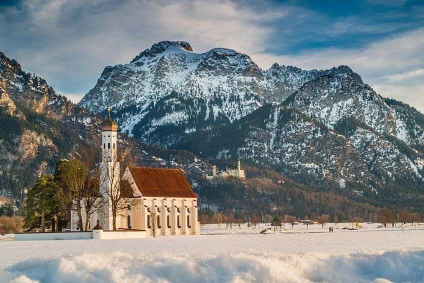 En kirke med et kirketårn, snødekte bjerge og en klar himmel. 2
