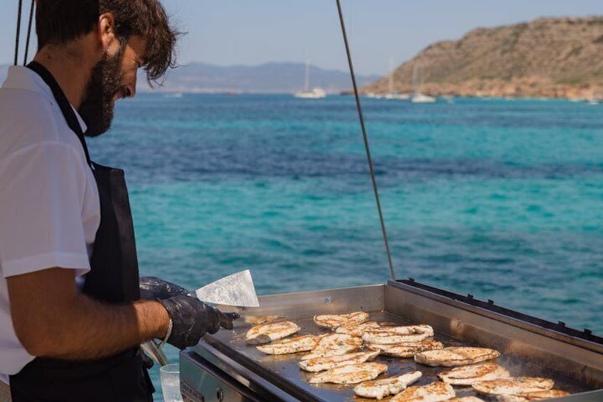 Eine Person bereitet Essen auf einem tragbaren Kocher am Meer zu. 1