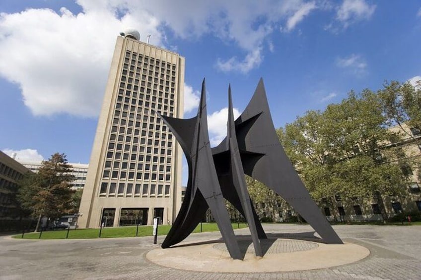 Een modern sculptuur in een open plein, met een hoog gebouw op de achtergrond. 2