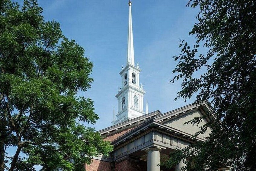 A church steeple with a tall spire, surrounded by trees. 4