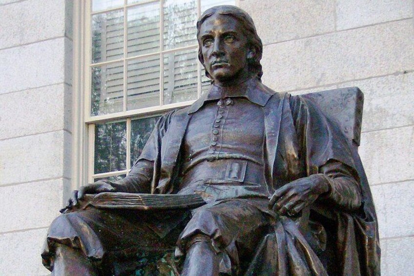 A bronze statue of a seated man with a book. 3