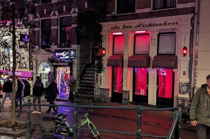 A street at night with a building with red lights and a sign that reads "In den Lichterkoi". 2