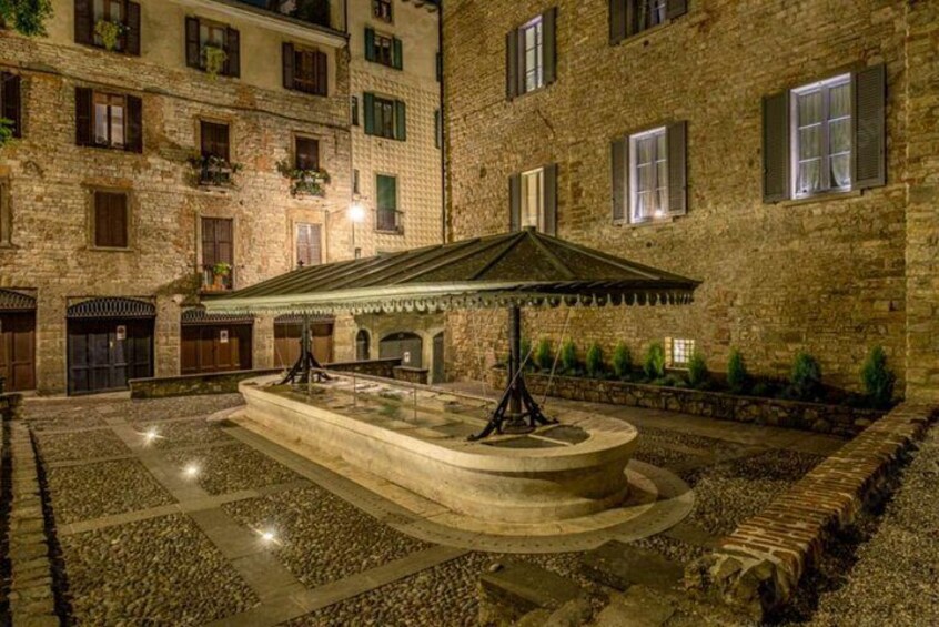 A courtyard with a central fountain, stone walls, and a building with multiple windows. 3