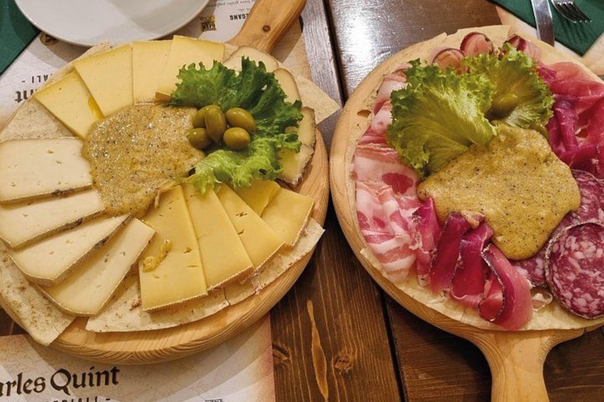 Zwei Holzbretter mit Käse, Oliven und Fleisch auf einem Tisch. 2