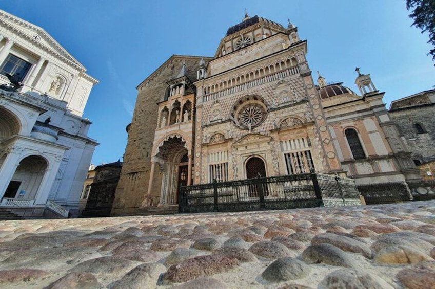 A historic building with intricate architecture, a large clock, and a stone staircase leading up to it. 1