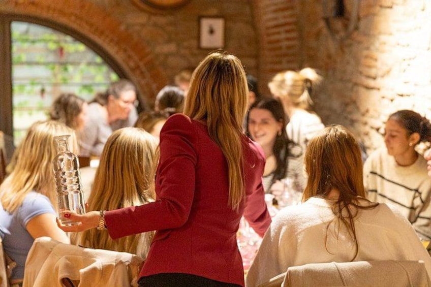 A person in a red jacket standing in a restaurant with brick walls and a large arched window. 2
