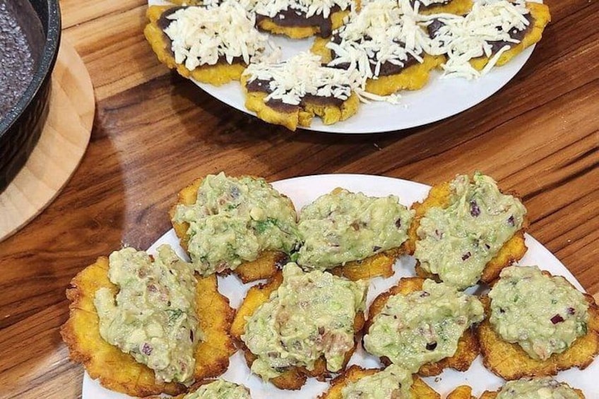Une assiette de bananes plantains frites, garnie de fromage râpé et de guacamole. 2