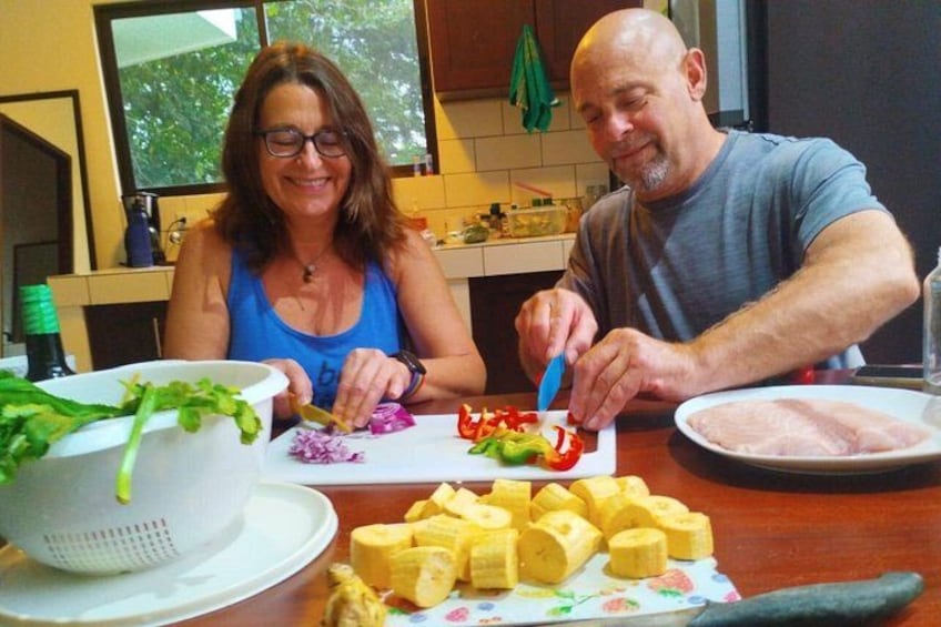 Deux personnes préparent un repas à une table de cuisine, avec des légumes, une passoire et une assiette de nourriture. 5