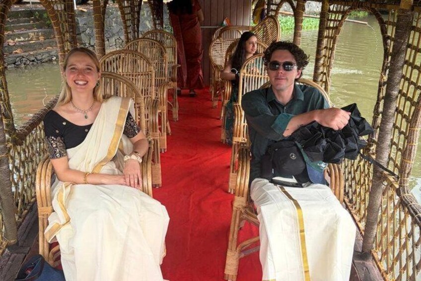 People seated on wicker chairs in a boat with a red carpet. 4