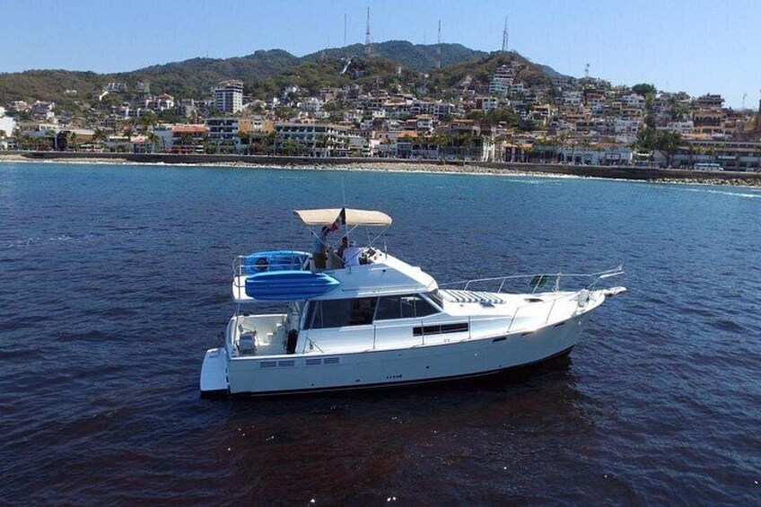 A white motorboat on calm water with a coastal town in the background. 2