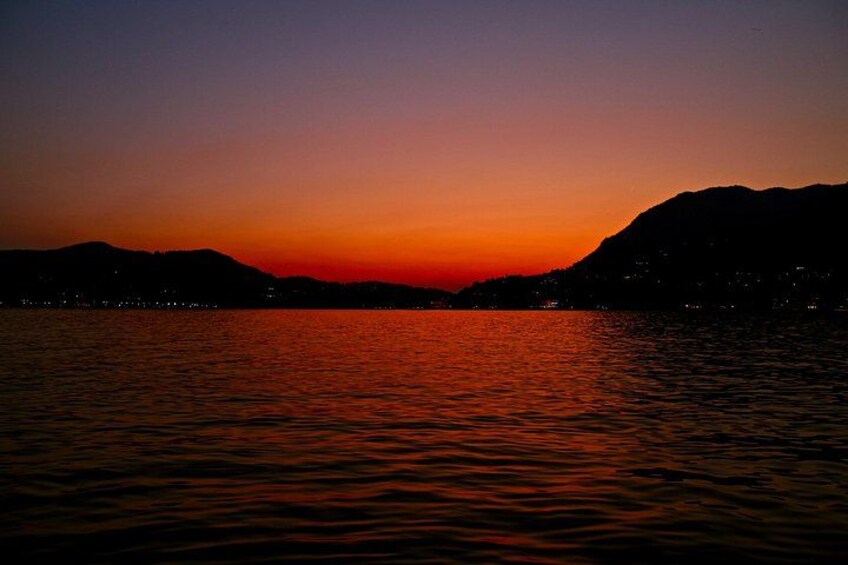 Een zonsondergang boven een wateroppervlak met bergen op de achtergrond. 4