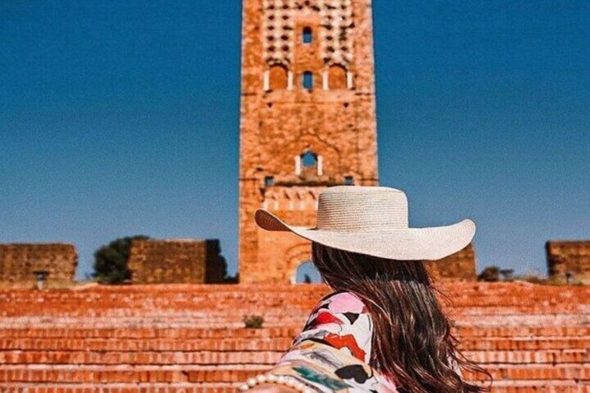 A person wearing a cowboy hat standing in front of a tall, ancient tower. 1