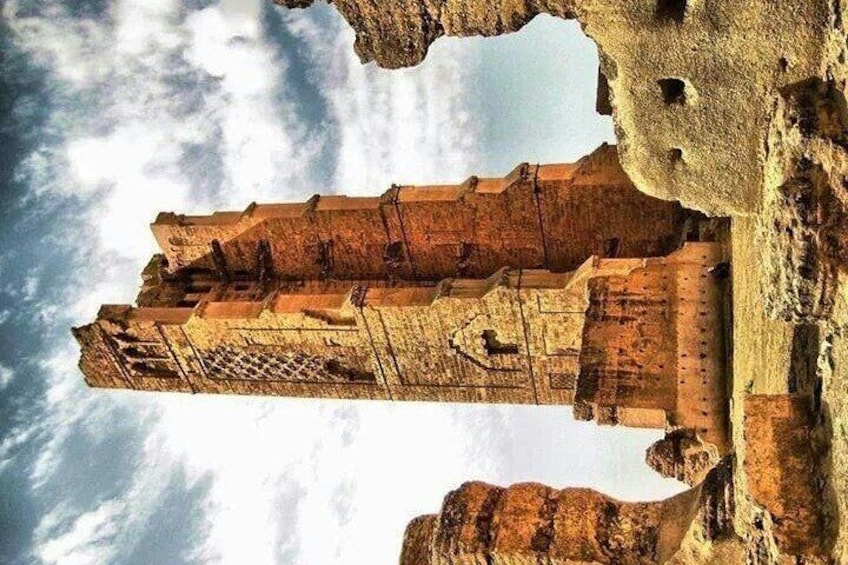 A large, ancient stone structure with intricate carvings, set against a backdrop of a cloudy sky. 4