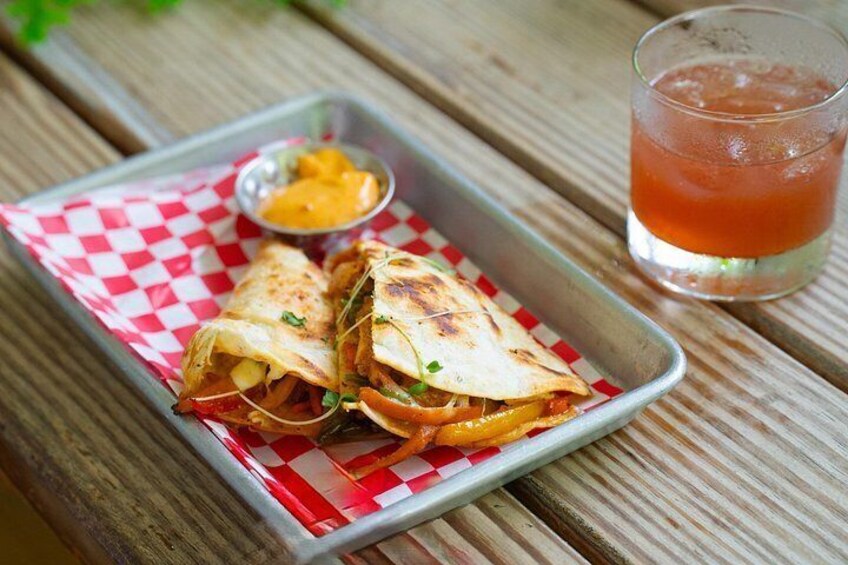 A meal consisting of a quesadilla, a side of salsa, and a glass of iced tea on a wooden table. 4