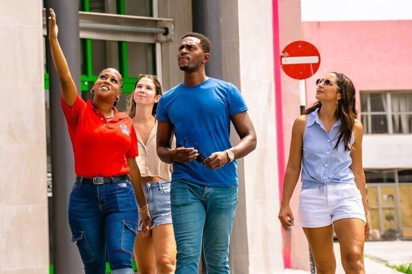 A group of people walking outdoors, with a building and a no entry sign in the background. 5