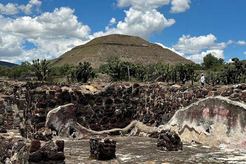 A rocky landscape with a large hill, cacti, and a person standing on a rock. 3