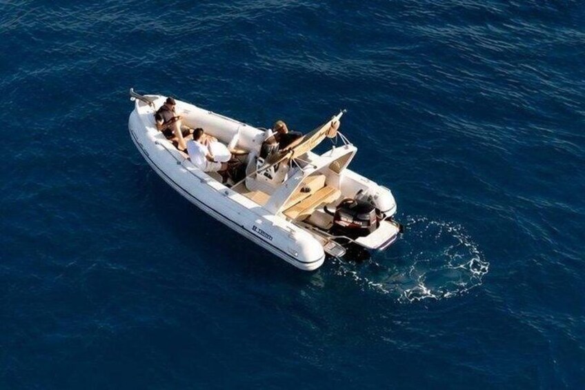 A white motorboat with passengers on a clear blue sea. 3