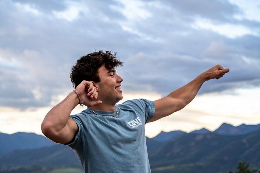 A person pointing towards the horizon with mountains in the background. 3