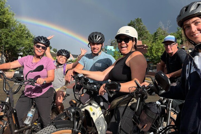 A group of people on bicycles with a rainbow in the background. 5