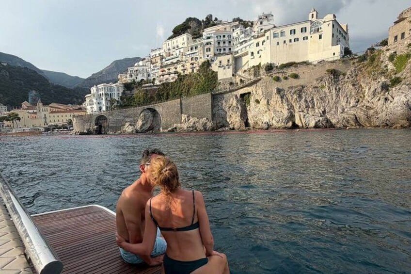 A couple sitting on a boat with a coastal town in the background. 1