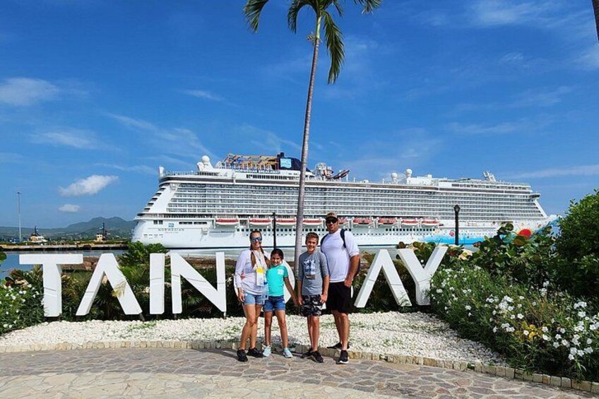 Un navire de croisière, un palmier et un panneau avec le mot « TAYNAY » devant une étendue d’eau. 5