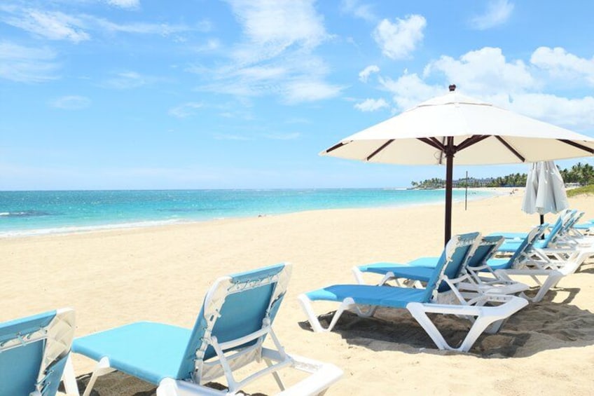 Une plage avec des chaises longues bleues et un parasol blanc. 1