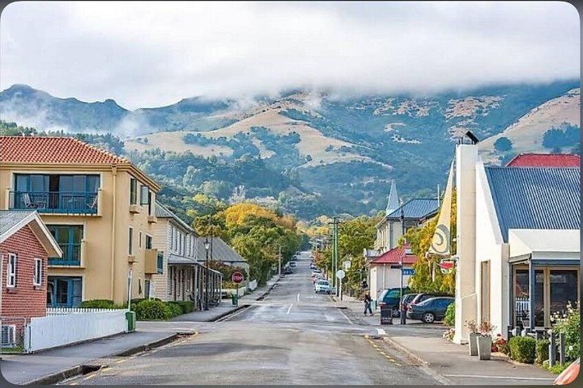 A street with buildings, parked cars, and mountains in the background. 1