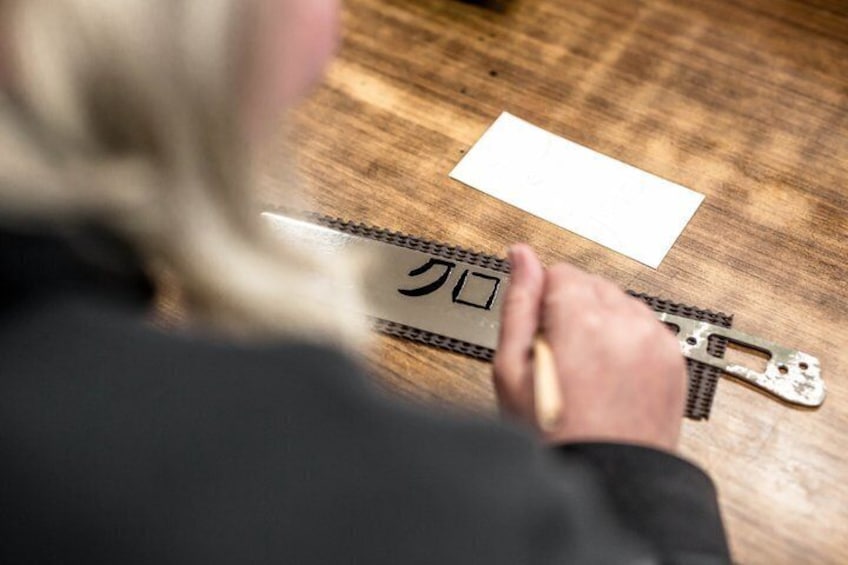 A person using a metal ruler to measure a piece of paper on a wooden surface. 2