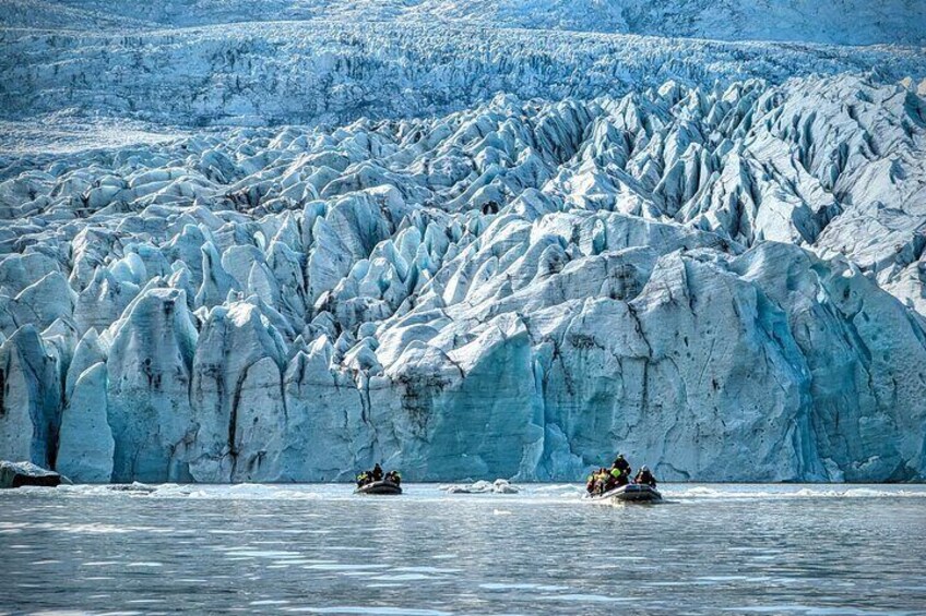 A glacier with two boats on the water. 5