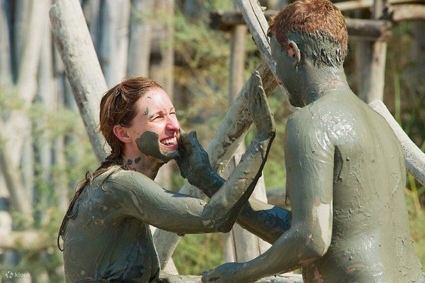 Two people covered in mud, engaged in an activity outdoors. 4