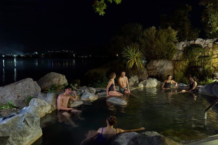 A group of people in a heated outdoor pool at night. 3