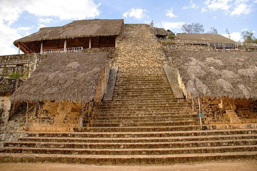 A stone staircase leading up to a thatched-roof structure with a balcony. 4