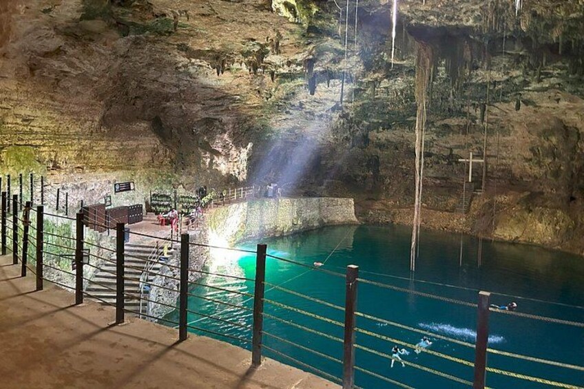 A cave with a pool of water, a wooden walkway, and a rope barrier. 3