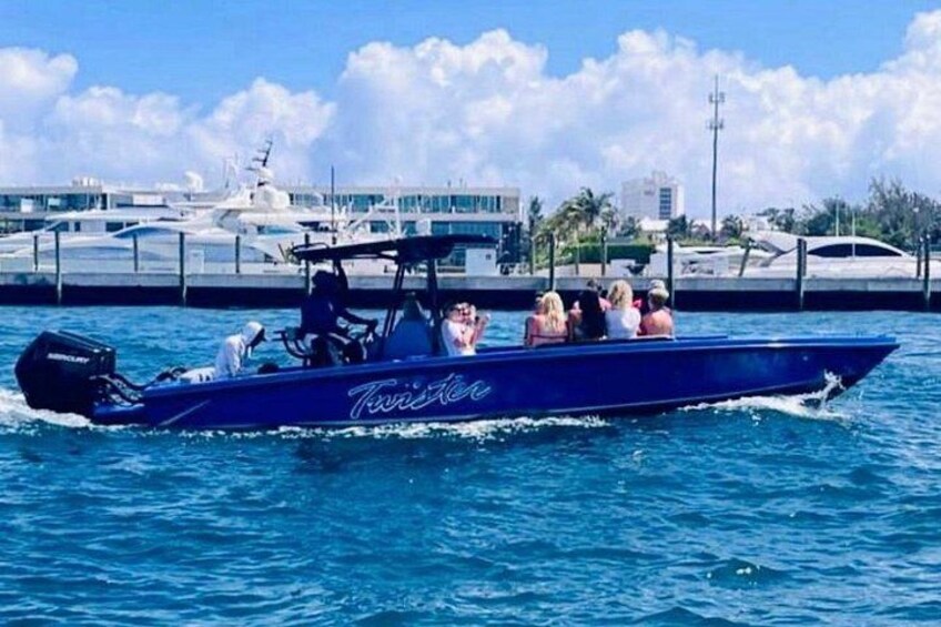 A blue speedboat with the name 'Twist' on the side, moving on the water with several people on board. 3