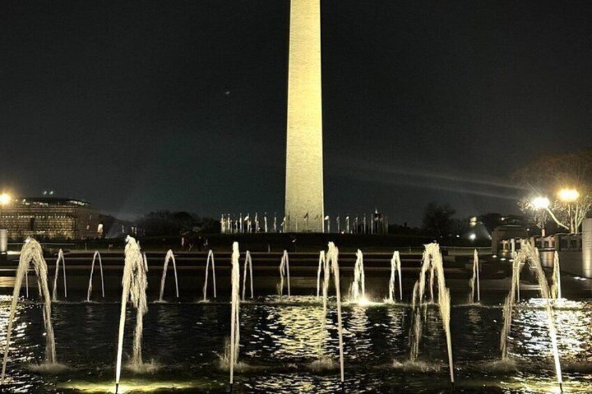A nighttime view of the Washington Monument with a water fountain in the foreground. 2
