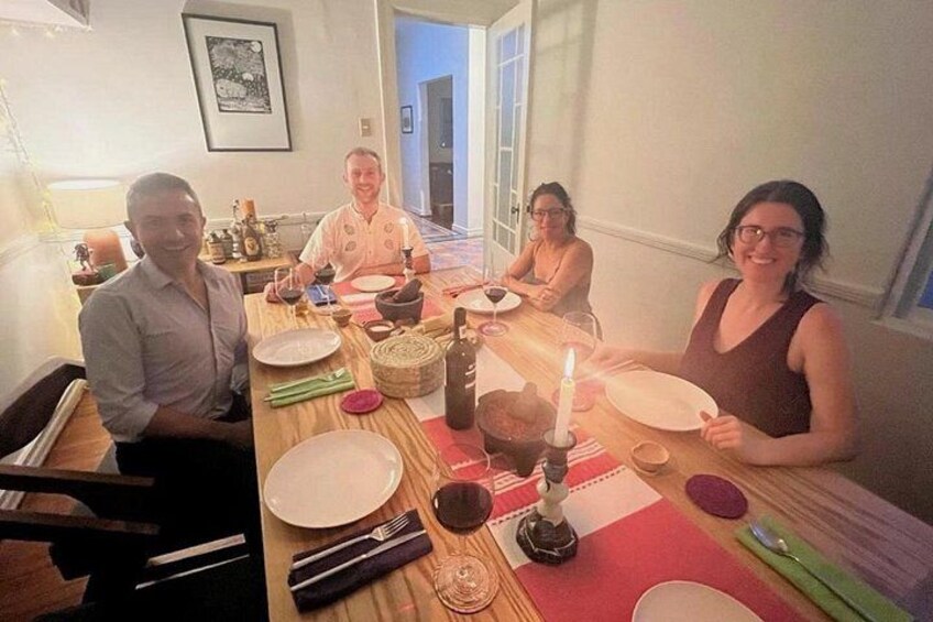 A group of people sitting around a table with plates, cutlery, and a candle. 4